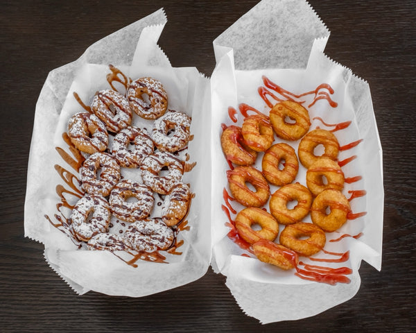Two boxes of mini donuts with chocolate and strawberry drizzle